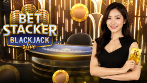 Bet Stacker Blackjack 真人二十一點遊戲，亞洲女性荷官手持金色 K 撲克牌，搭配金色娛樂場背景與藍色二十一點牌桌。